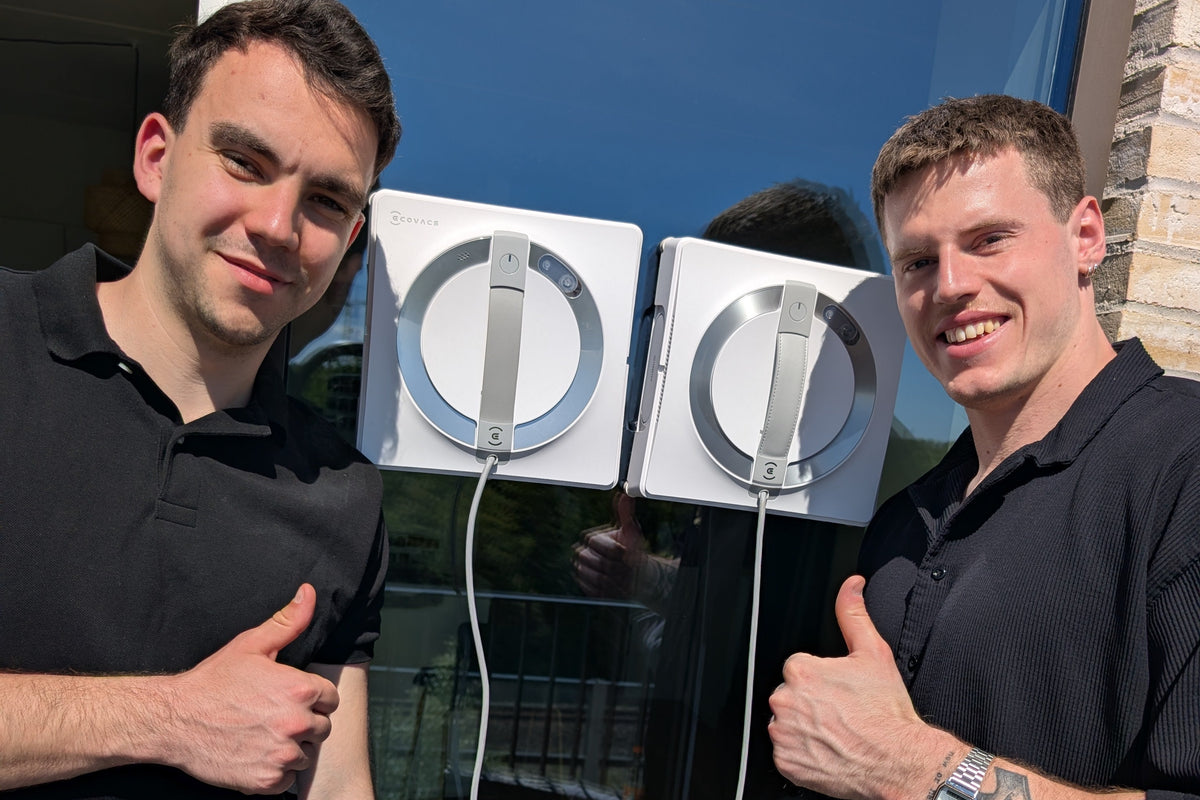 An image of 2 men standing next to window cleaning robots