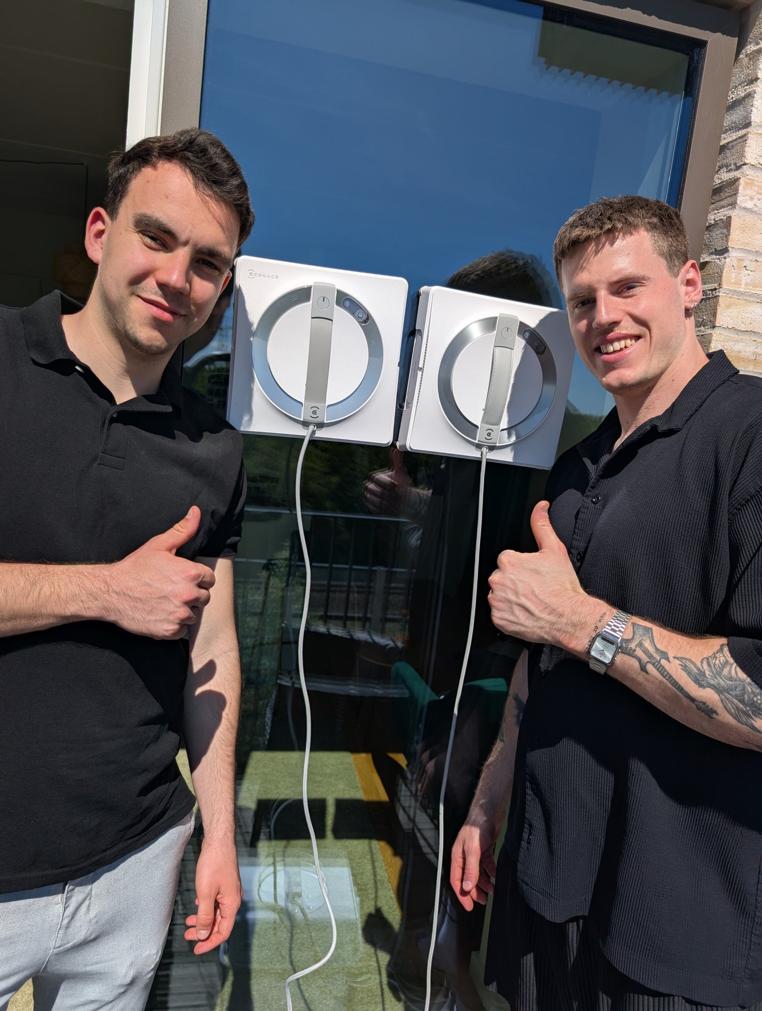 An image of 2 men standing next to window cleaning robots